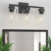 Espird matte black vanity light with three clear glass shades over a mirror.