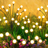 inBoboli Solar Firefly Lights with swaying stems illuminate your garden at night along pathways.