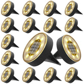Joomer solar ground light with 8-LED disc illuminating a garden path with warm white glow.