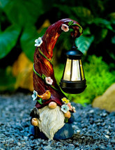 Pohabery Gnome Garden Statue with lantern glowing softly in a garden setting.