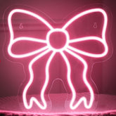 Retisee Pink Bow neon sign on wall with soft pink glow for chic decor.
