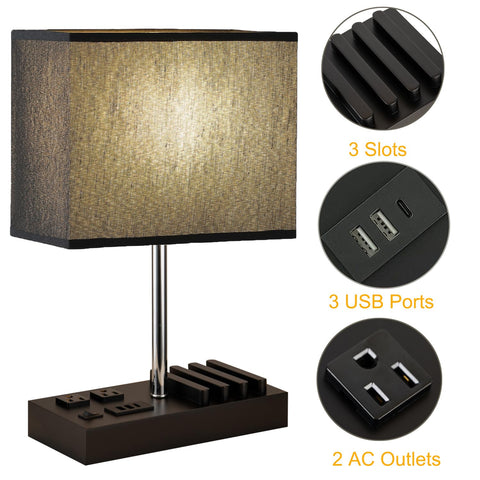 Briever table lamp with two AC outlets powering devices at desk.