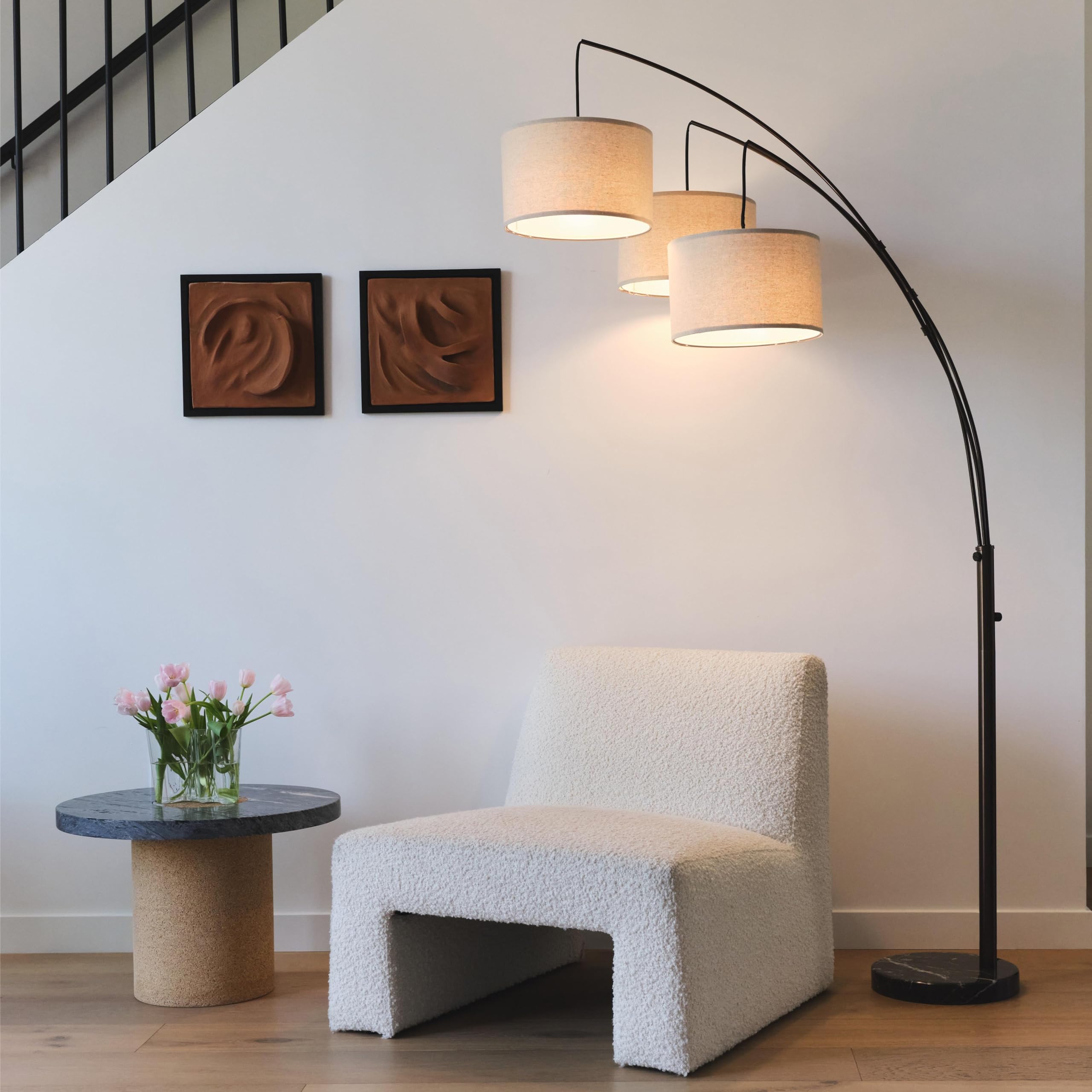 Brightech Trilage Arc lamp emits warm LED light ideal for reading.