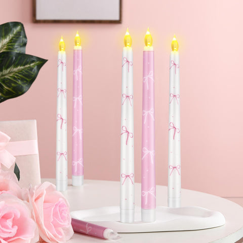 Conelist Coquette pink bow flameless taper candle on windowsill adding soft ambiance.