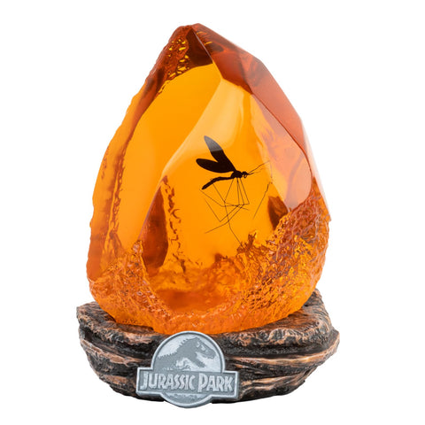 Grupo Erik Official Jurassic Park Lamp with amber resin base provides warm ambient lighting.