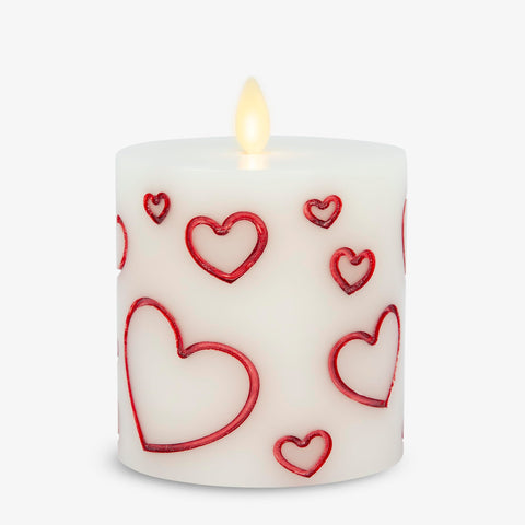Luminara Debossed Hearts red pillar candle close-up with lifelike flicker for romantic ambiance.