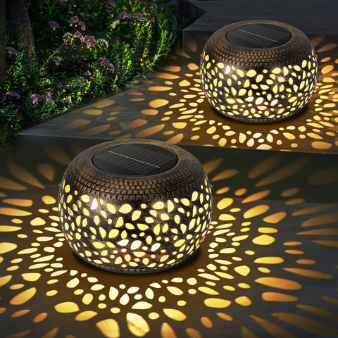 NFEVER solar lantern with round hollow metal frame glows warmly in gardens.