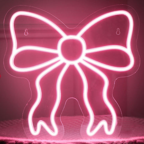 Retisee Pink Bow neon sign on wall with soft pink glow for chic decor.