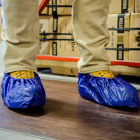 ShuBee shoe covers are shown in use on plumbing or construction sites.