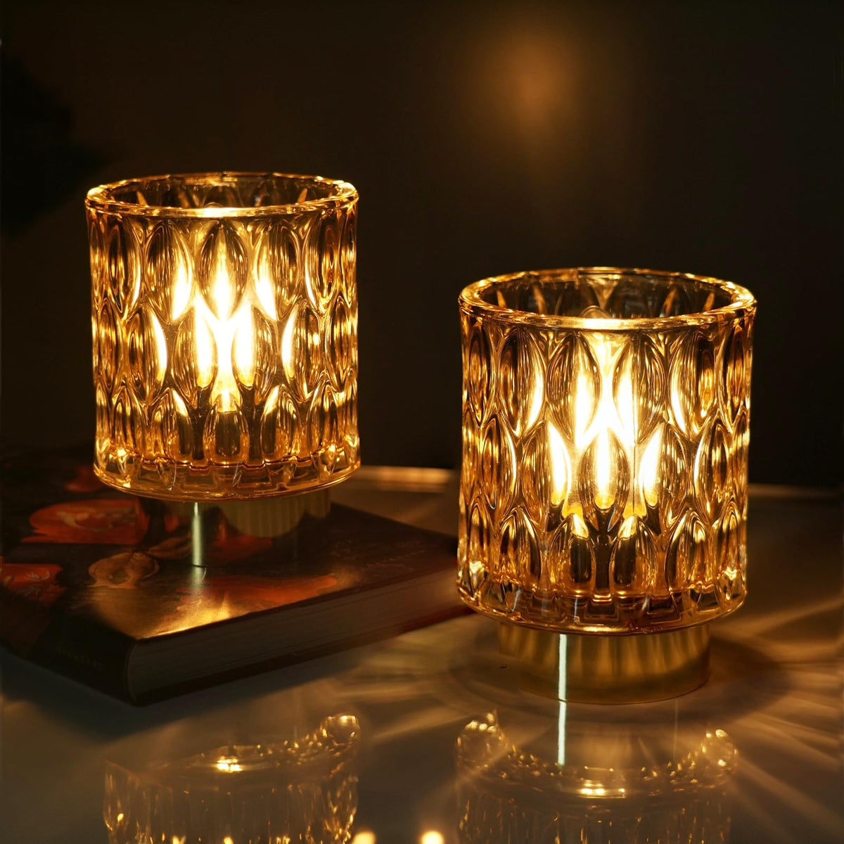 SJIE battery-operated lamp with glass base glowing softly on a nightstand.