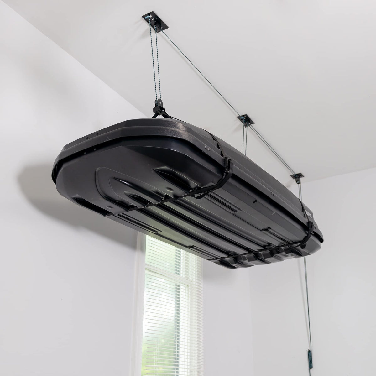 Teal Triangle ceiling storage hoist lifting a cargo box overhead for clutter-free garage.