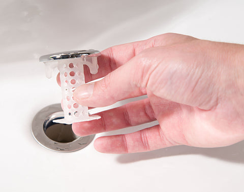 Close-up of TubShroom chrome edge with hair trapped around the unit.