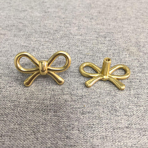 Gold bow knob decorates a cabinet door with durable hardware.