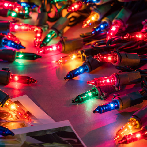 Close-up of YULETIME glass bulbs on green wire, warm multicolor glow